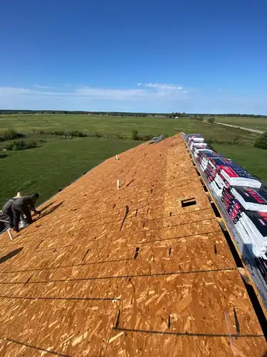 Pinnacle crew laying new decking with shingle bundles staged on the ridge in Crane, Missouri