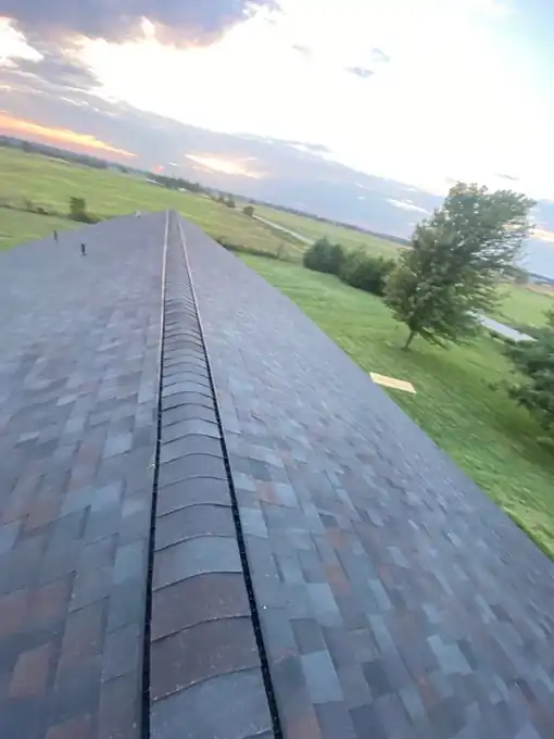 Ridge of a new multi-tone shingle roof at sunset over open farmland near Crane, Missouri