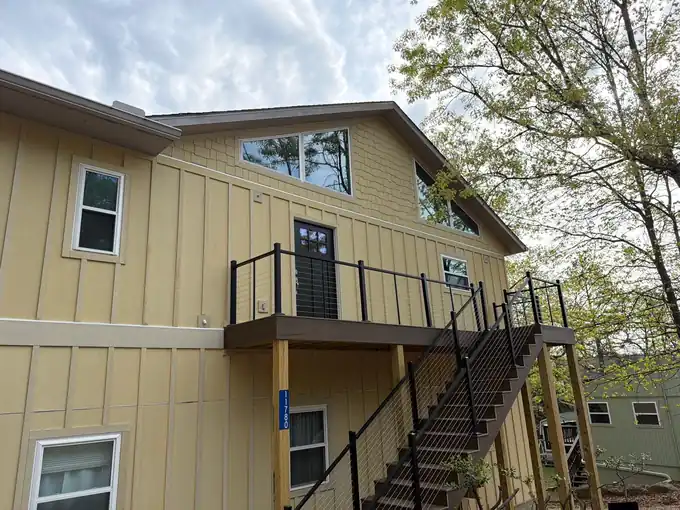 Primed James Hardie board and batten siding with shake accents on a lakeside home with a deck and cable railings