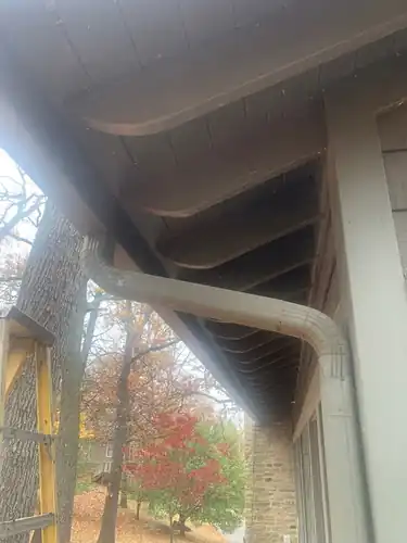 New downspout elbow under the eave of a stone home