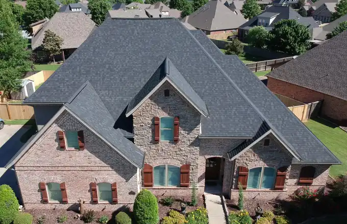 Drone view of a brick and stone home in Rogers with a finished Owens Corning Duration roof