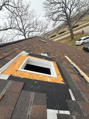Skylight opening cut through OSB with shingles stripped back around it