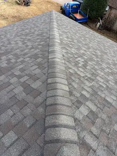 A CertainTeed Landmark Weatherwood ridge line running away from the camera on a finished roof in Springdale