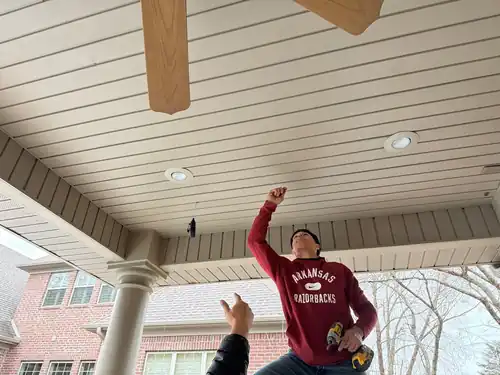 A Pinnacle installer fitting soffit panels under a porch ceiling