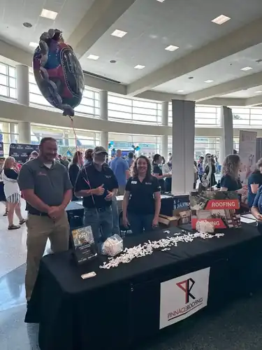 Three members of the Pinnacle Roofing team standing at their booth at a local expo